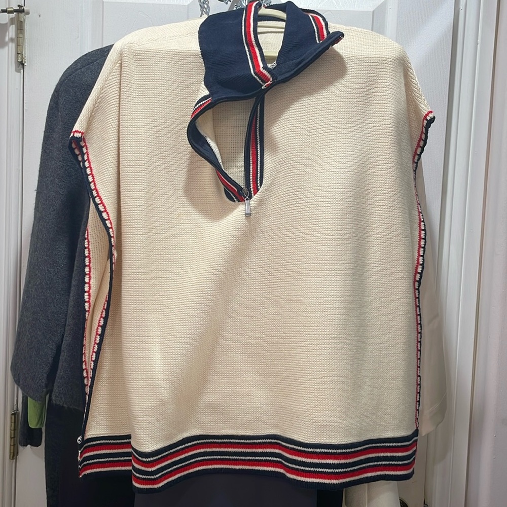 Cream colored poncho with red and navy stripes on the edges